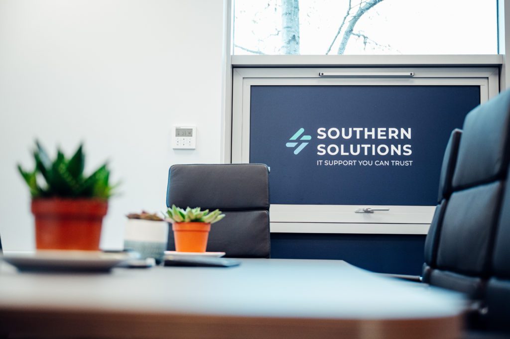 Succulent plants on a computer desk and a sign in the background, "Southern Solutions IT support you can trust".